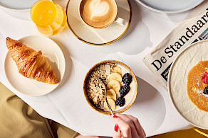 Ontbijtcompositie met croissant, cappuccino, granolakom met bessen en banaan, vers fruit op een wit tafelblad